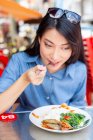 Atraente asiático mulher comer comida no rua café — Fotografia de Stock
