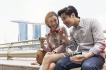 Jovem asiático casal usando smartphone em Cingapura — Fotografia de Stock