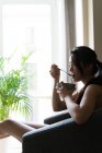 Cinese giovane donna avendo colazione in il divano io — Foto stock