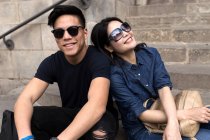 Young Chinese in sunglasses sitting together on steps — Stock Photo