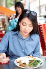 Приваблива азіатська жінка їсть їжу у вуличному кафе — стокове фото