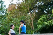 Две женщины наверстывают упущенное перед тренировкой в Ботаническом саду, Сингапур — стоковое фото