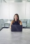Молода азіатська бізнес-леді працює з ноутбуком в сучасному офісі — стокове фото