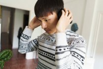 Jovem asiático homem vestindo fones de ouvido em casa — Fotografia de Stock