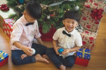 Frères jouant avec la décoration du sapin de Noël et s'amusant. — Photo de stock