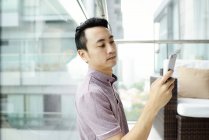 Ältere asiatische casual Mann mit smartphone zu Hause — Stockfoto