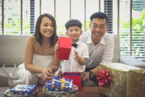 Madre e padre guardando il loro figlio aprire i suoi regali di Natale nella loro casa a Singapore . — Foto stock