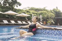 Joven hermosa mujer asiática en traje de baño divertirse en la piscina - foto de stock