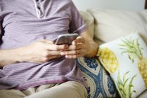Cropped image of man using smartphone at home — Stock Photo