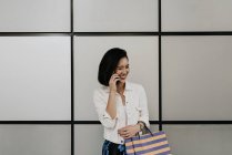Young casual asian woman using smart at shopping mall — Stock Photo