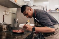 Молодий азіатський шеф-кухар готує на кухні ресторану — стокове фото
