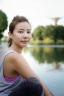 Junge sportliche asiatische Frau sitzt im Park — Stockfoto