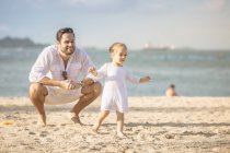 Счастливая кавказская семья на пляже, отец играет с дочерью — стоковое фото