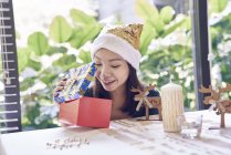 Glücklich junge asiatische Frau feiert Weihnachten und packt Geschenk aus — Stockfoto