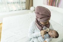 Asian muslim mother feeding her baby at home — Stock Photo