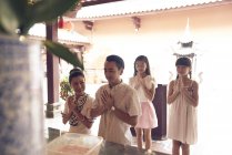 Молода щаслива азіатська сім'я молиться святиня — стокове фото