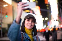 Ragazza viaggiatore prendendo selfie gioioso e felice sorridente in Time square — Foto stock