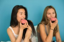 Две молодые женщины веселятся с пончиками — стоковое фото