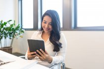 Young woman using tablet in modern office — Stock Photo