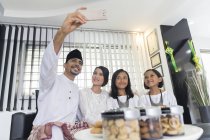 Young asian family celebrating Hari Raya together at home and taking selfie — Stock Photo