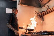 Junger asiatischer Koch kocht in Restaurantküche — Stockfoto