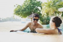 Young attractive asian couple relaxing in swimming pool — Stock Photo
