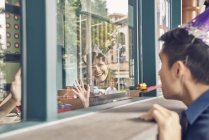 Юнак азіатських дивлячись через вікно на жінку — стокове фото