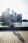 Young sporty asian woman making yoga against business district — Stock Photo