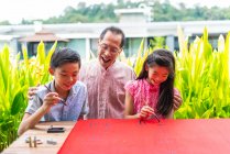 Счастливая азиатская семья вместе, дедушка и внуки рисуют иероглифы — стоковое фото
