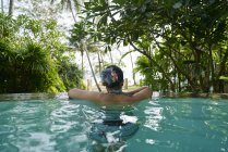 Вид сзади на молодую женщину, отдыхающую в бассейне — стоковое фото