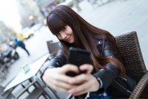 Junge Frau mit langen Haaren macht ein Selfie mit ihrem Smartphone — Stockfoto