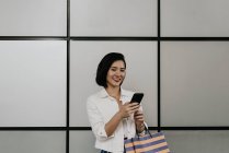 Giovane donna asiatica casuale utilizzando smartphone al centro commerciale — Foto stock