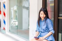 Привлекательная взрослая азиатка с помощью смартфона — стоковое фото