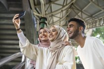Группа счастливых друзей-мусульман, делающих селфи на смартфоне — стоковое фото