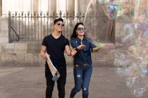 Beautiful young asian couple spending holiday in Barcelona and looking on the big bubbles — Stock Photo