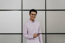 Молодой случайный азиатский мужчина, использующий смартфон — стоковое фото
