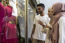Группа счастливых друзей-мусульман, которые ходят по магазинам и смотрят в витрину магазина — стоковое фото