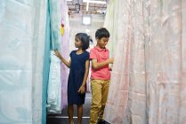 Hermanos comprando cortinas durante el Bazar Hari Raya en Geylang, Singapur - foto de stock