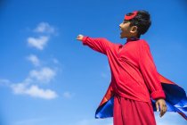 Superhero kid against blue sky background. — Stock Photo