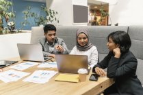 Jóvenes empresarios multiculturales que trabajan con dispositivos digitales en oficinas modernas - foto de stock