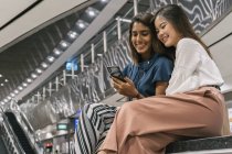 Young casual asian girls using smartphone together — Stock Photo