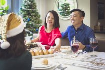 Singaporean coppia gode di una cena festiva con un amico nella loro bella casa durante le vacanze di Natale . — Foto stock