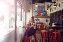 PROPIEDAD Joven hermosa mujer asiática usando teléfono inteligente en la cafetería - foto de stock