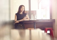 Junge schöne asiatische Frau sitzt im Restaurant — Stockfoto