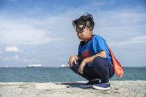 Ritratto di un bambino supereroe accovacciato . — Foto stock