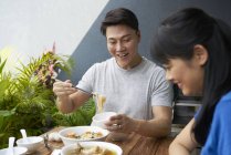 Feliz asiático pareja comer juntos en casa - foto de stock