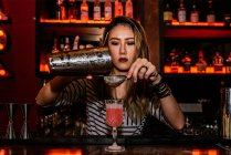 Portrait de jeune femme barman faisant cocktail au bar — Photo de stock
