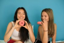 Дві молоді жінки розважаються з пончиками — стокове фото