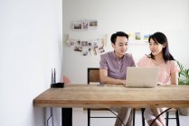 Mature asian casual couple using laptop at home — Stock Photo