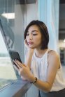 Giovane donna d'affari asiatica utilizzando smartphone in ufficio moderno — Foto stock